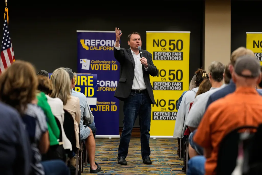 Republican Assembly member Carl DeMaio speaks at a rally against Proposition 50, with signs reading