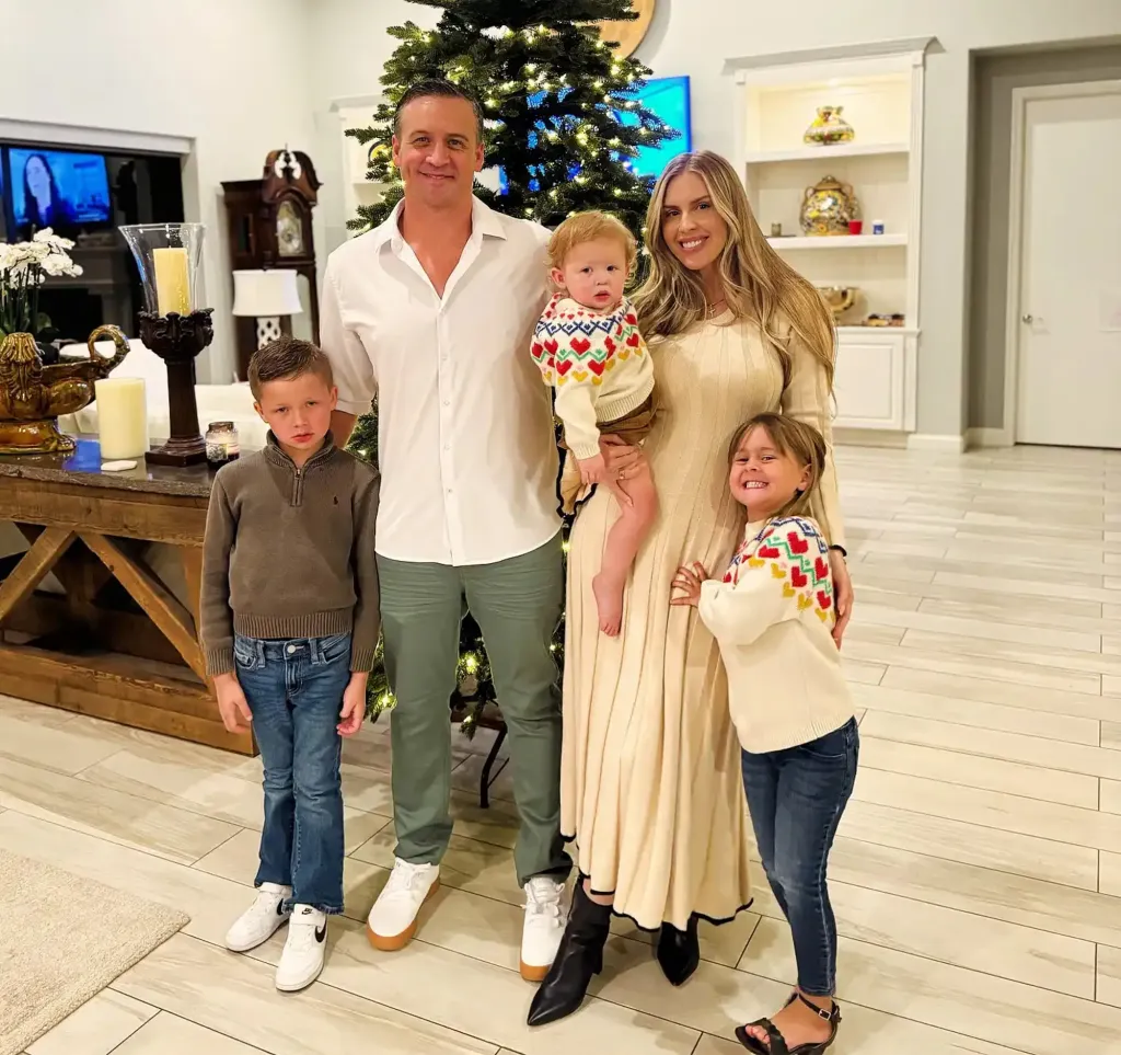 Ryan Lochte with his wife Kayla and their three children, Caiden, Georgia, and Liv, posing in front of a Christmas tree.