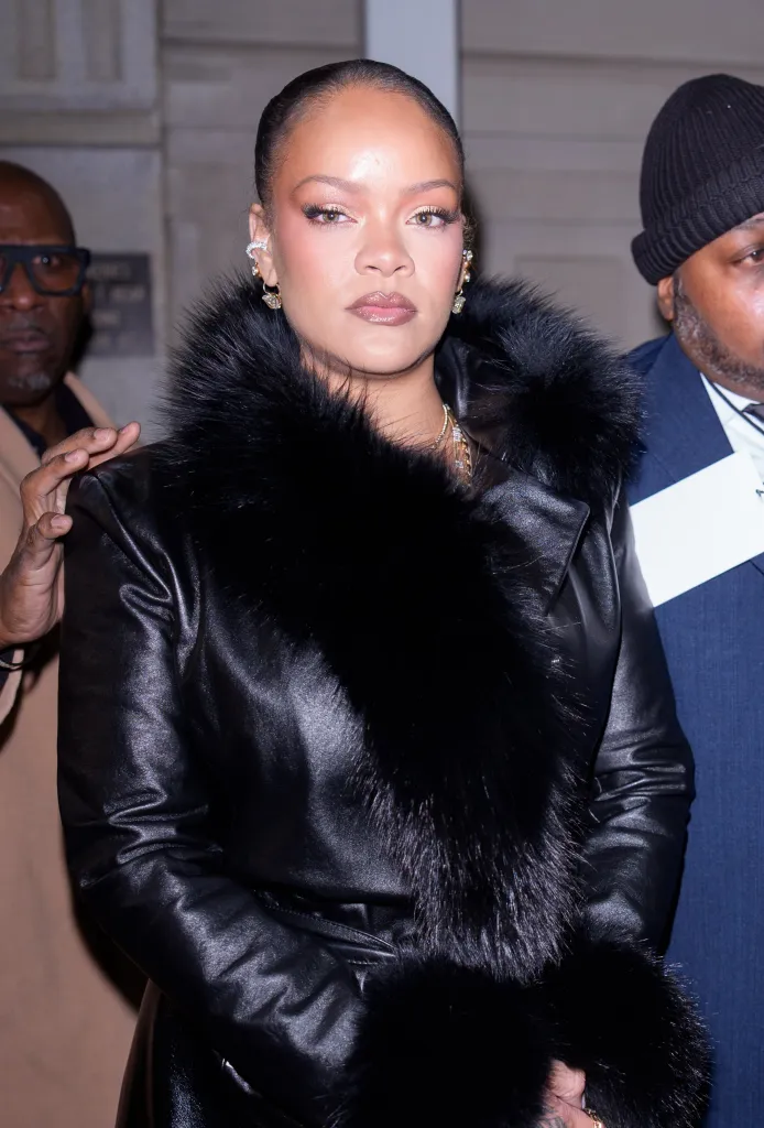 Rihanna wearing a black leather coat with a fur collar.