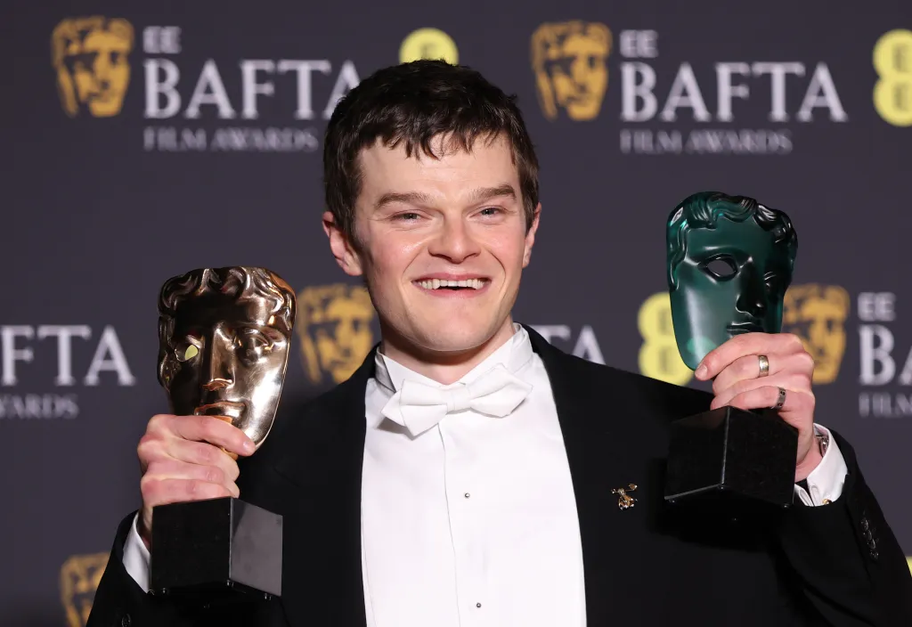 Robert Aramayo holding the Leading Actor Award and the EE Rising Star Award at the 2026 EE BAFTA Film Awards.