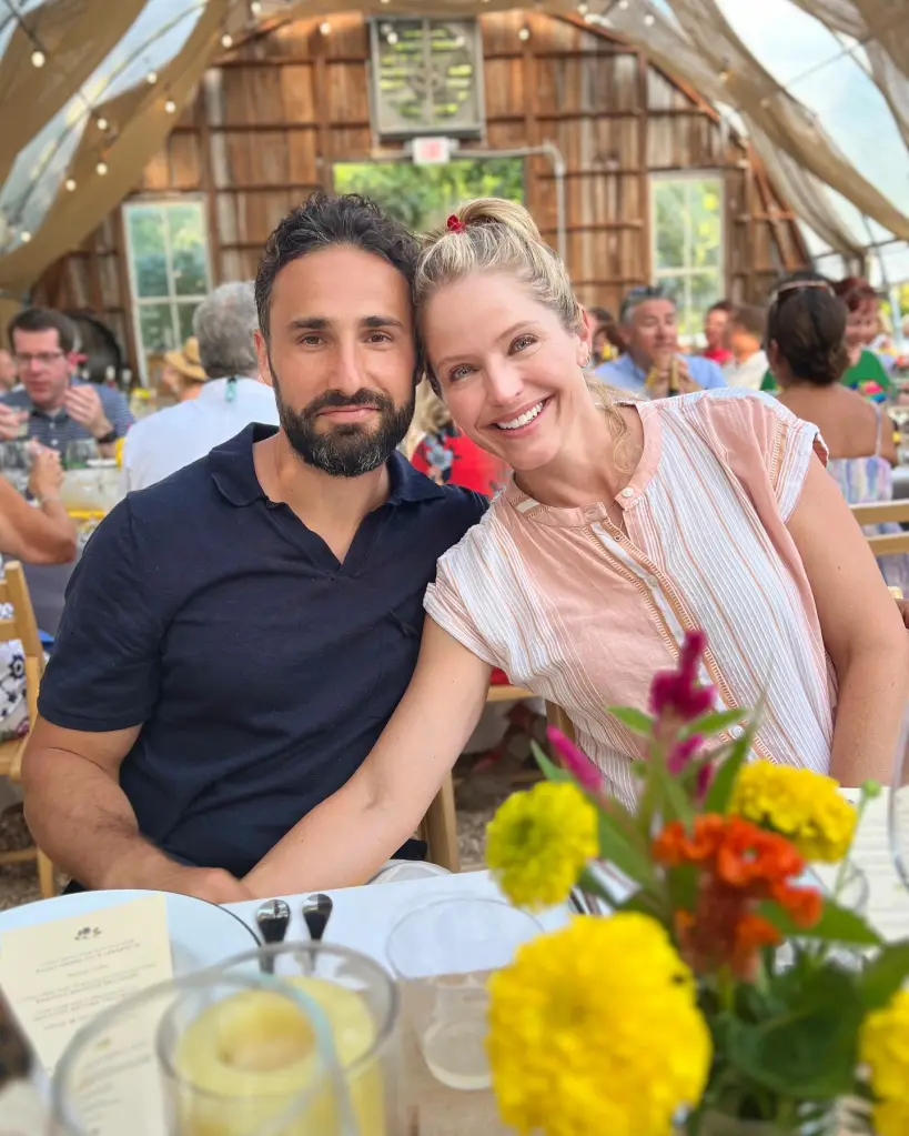Sara Haines and Max Shifrin smiling at a table with a centerpiece of colorful flowers.