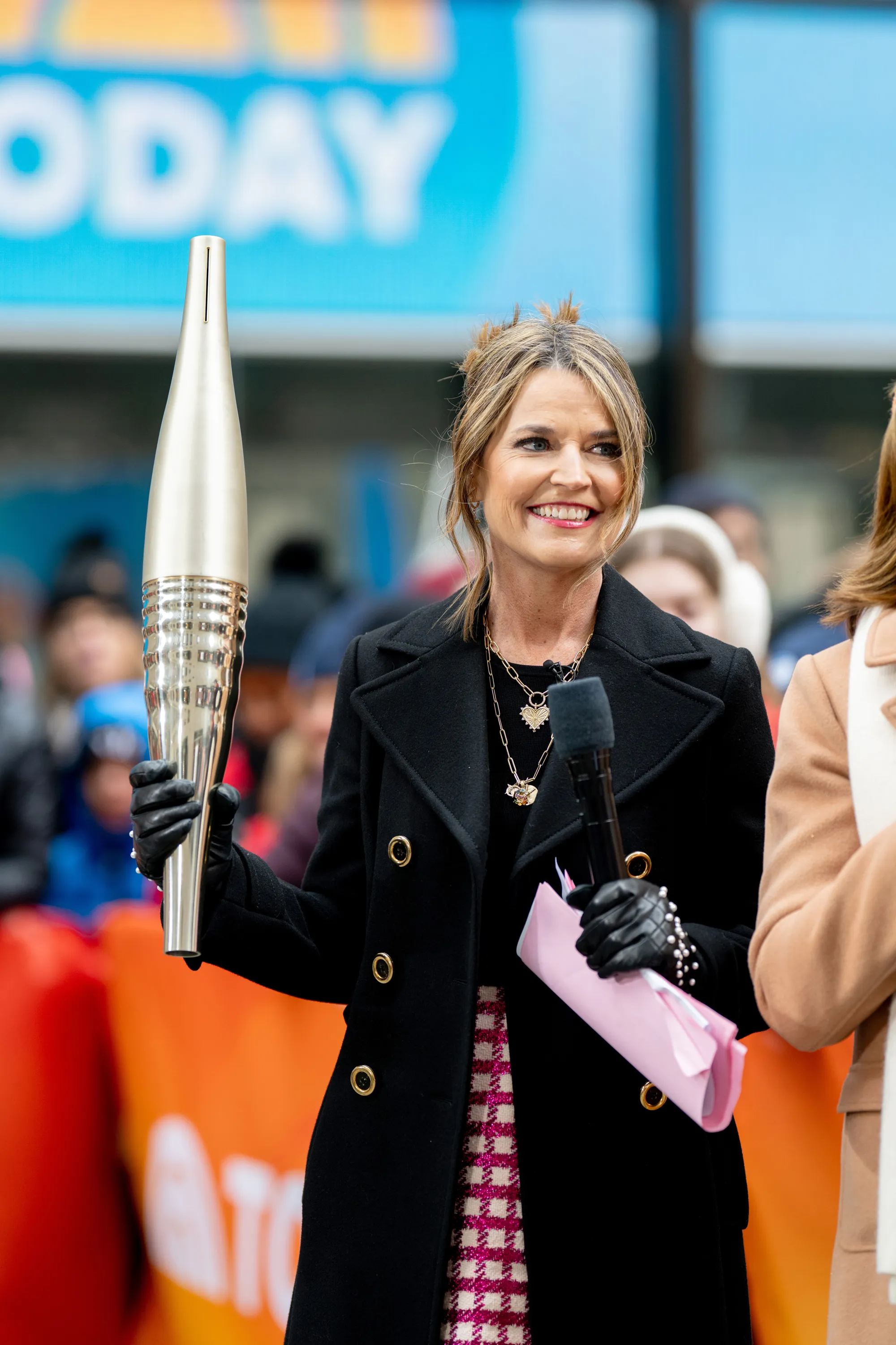 Savannah Guthrie holding a microphone and a torch.