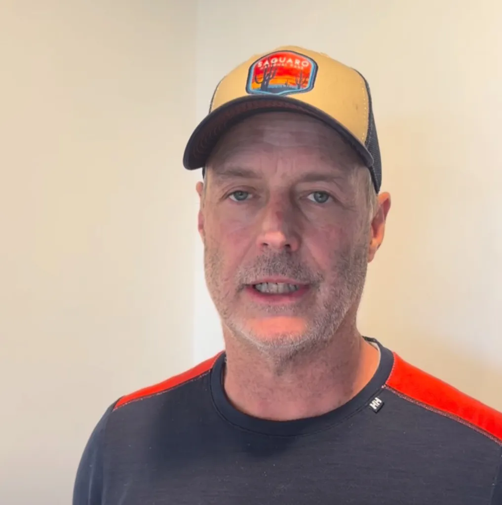 A man wearing a baseball cap with a Saguaro National Park logo.
