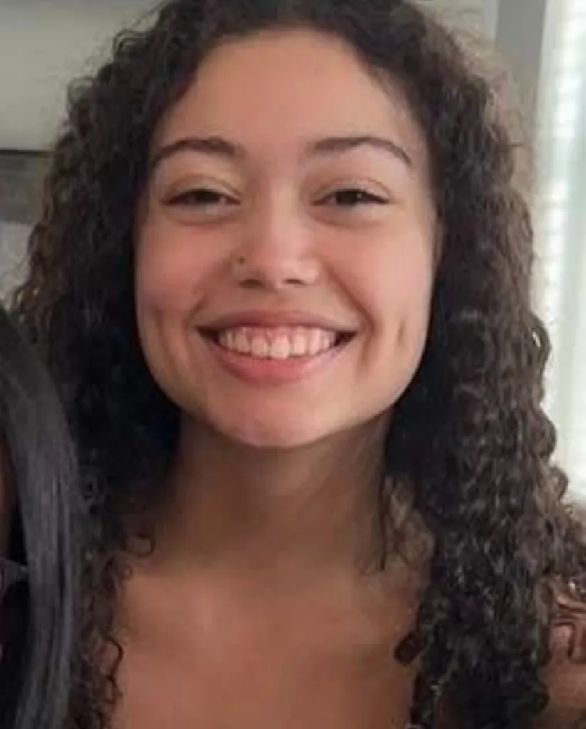 Headshot of Hailey Buzbee, a smiling teenage girl with long, curly brown hair and a nose ring.