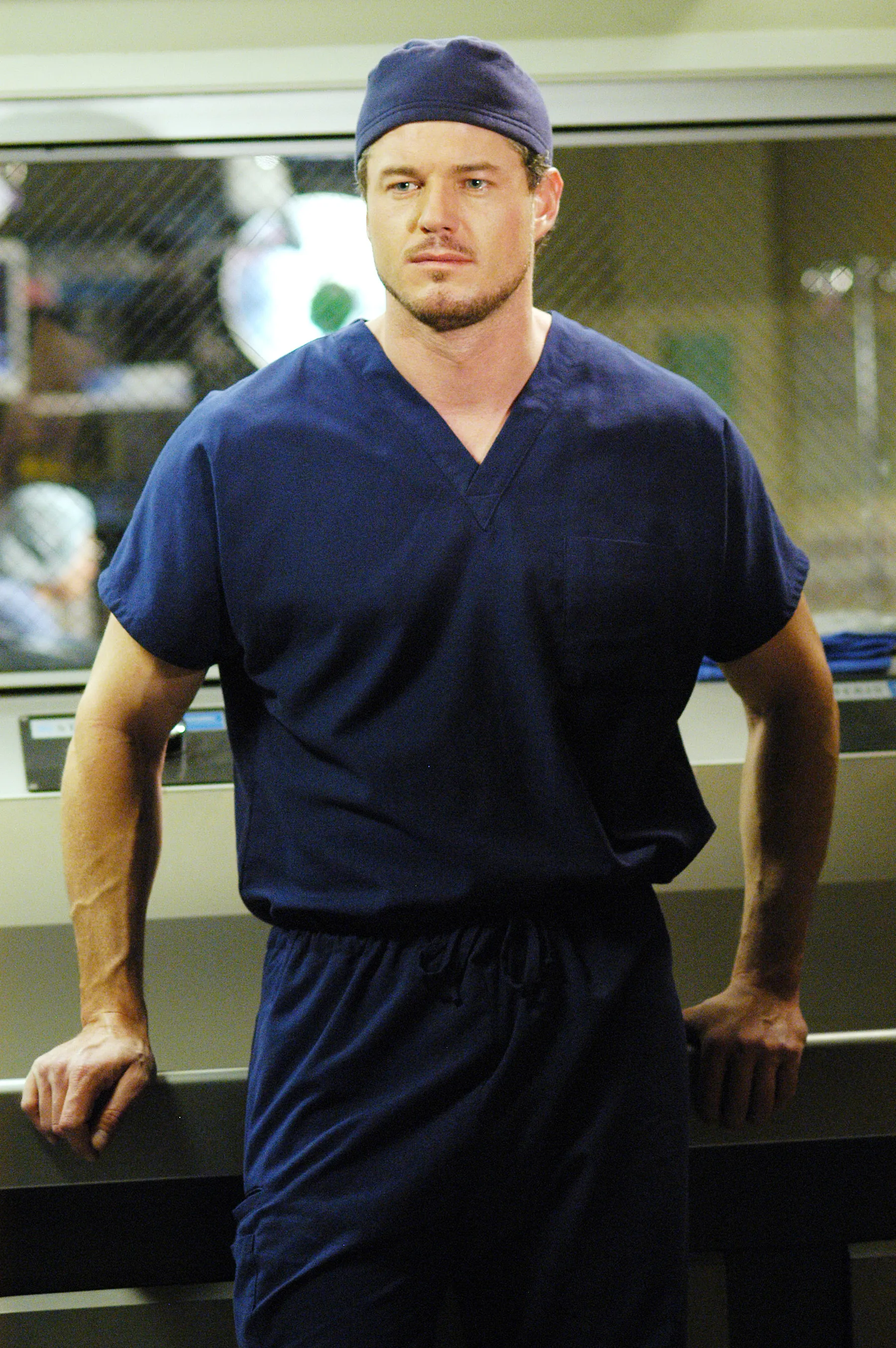 A man in blue scrubs and a blue surgical cap.