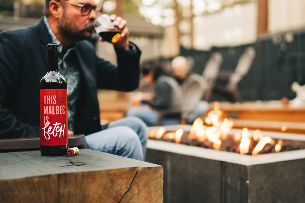 A man drinking wine from a bottle of eStCru Malbec with 
