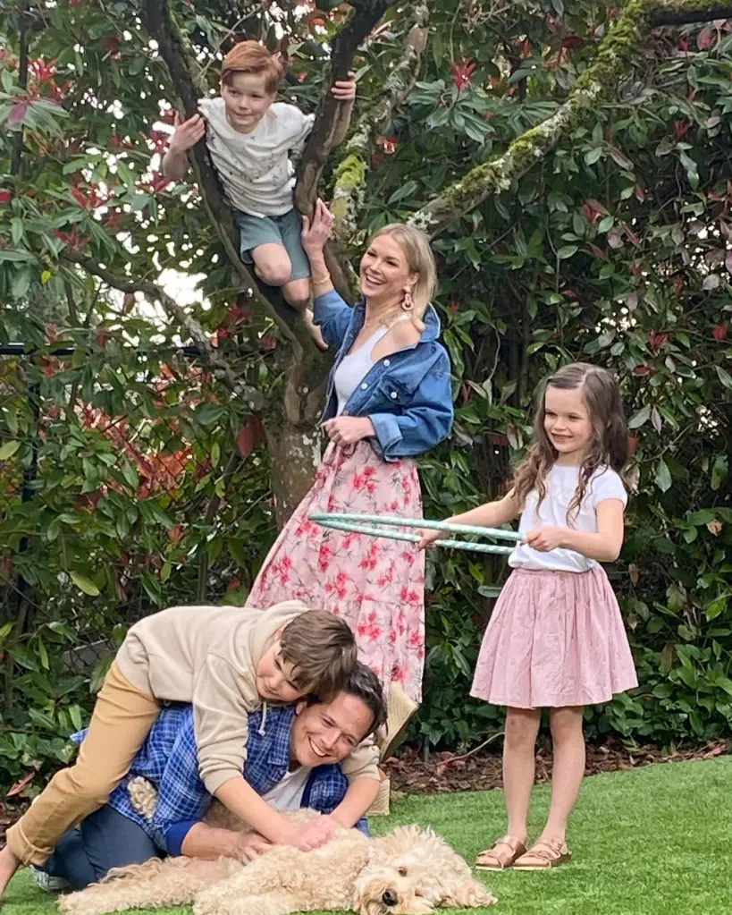 A family of five playing in a garden with a dog.