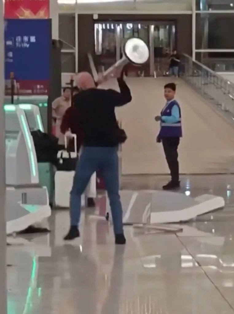 Man swinging stanchion at airport.
