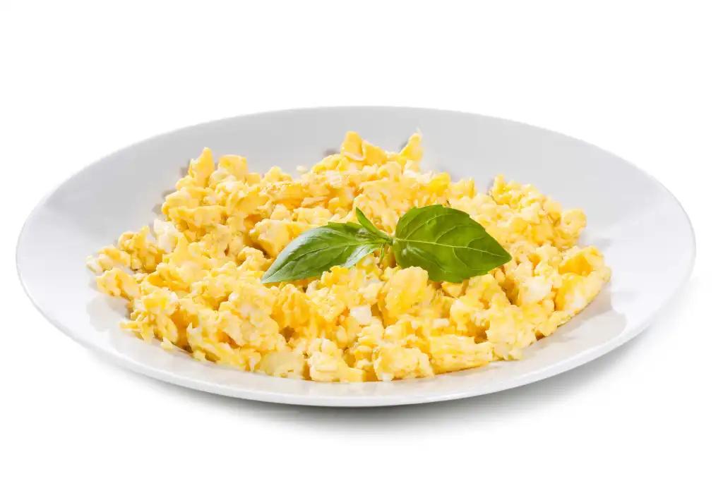 Scrambled eggs with basil on a white plate.