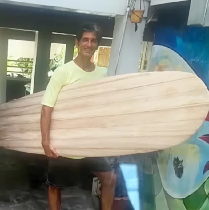 Slain surfer Kurt Van Dyke holding a wooden surfboard.