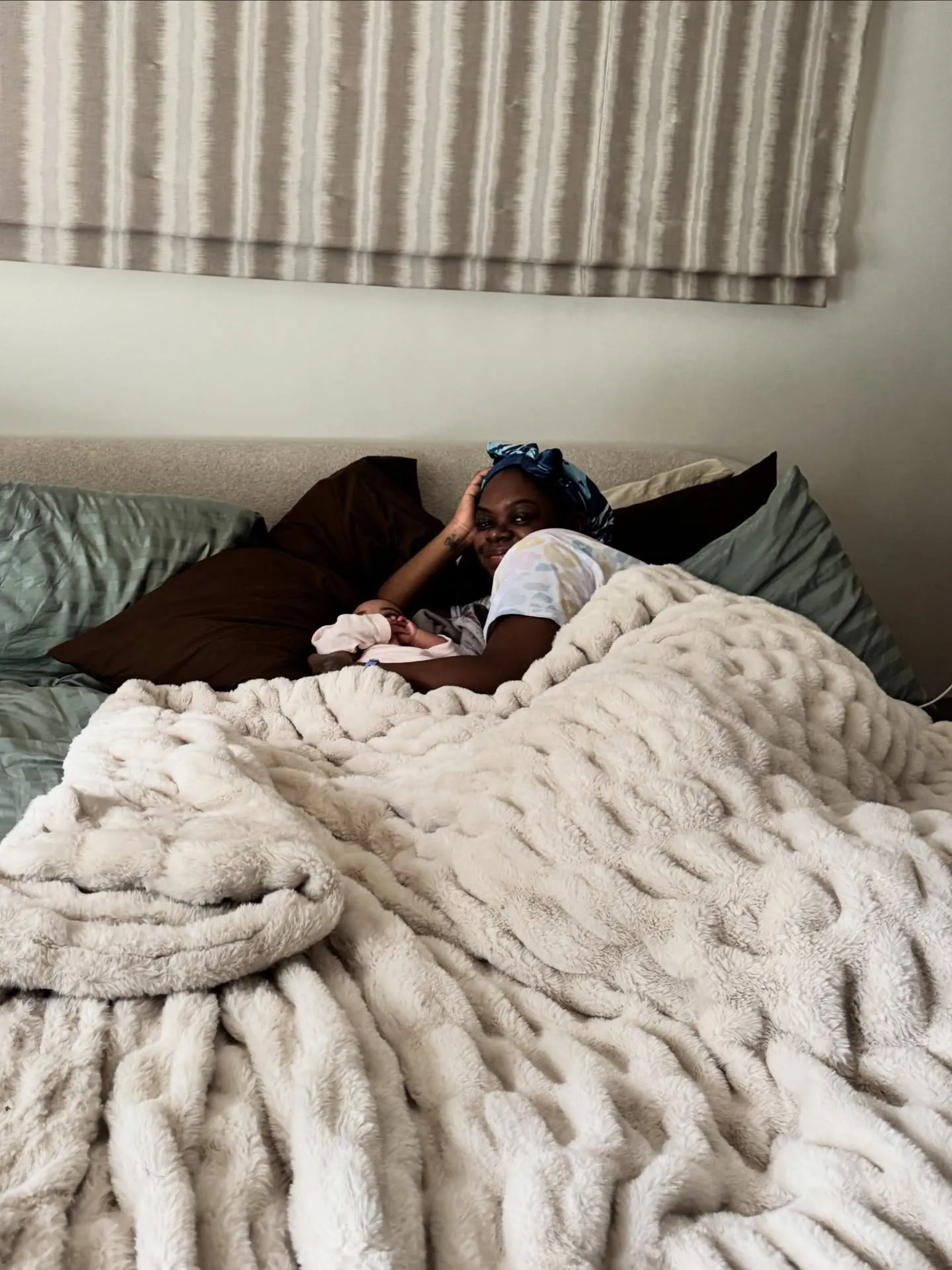 Cori Broadus lying in bed with a baby beside her.