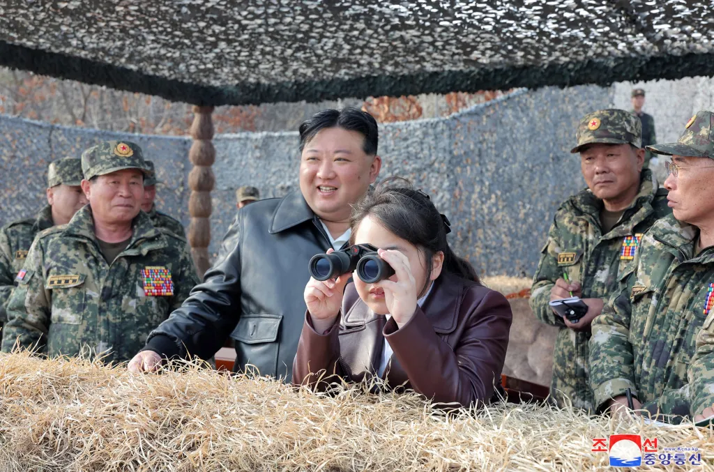 North Korean leader Kim Jong Un watches his daughter Ju Ae look through binoculars at a military training inspection.