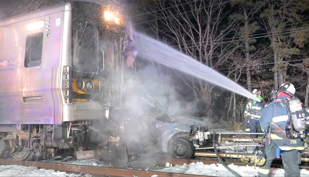 Firefighters extinguish a blaze at the scene of a train and car collision.
