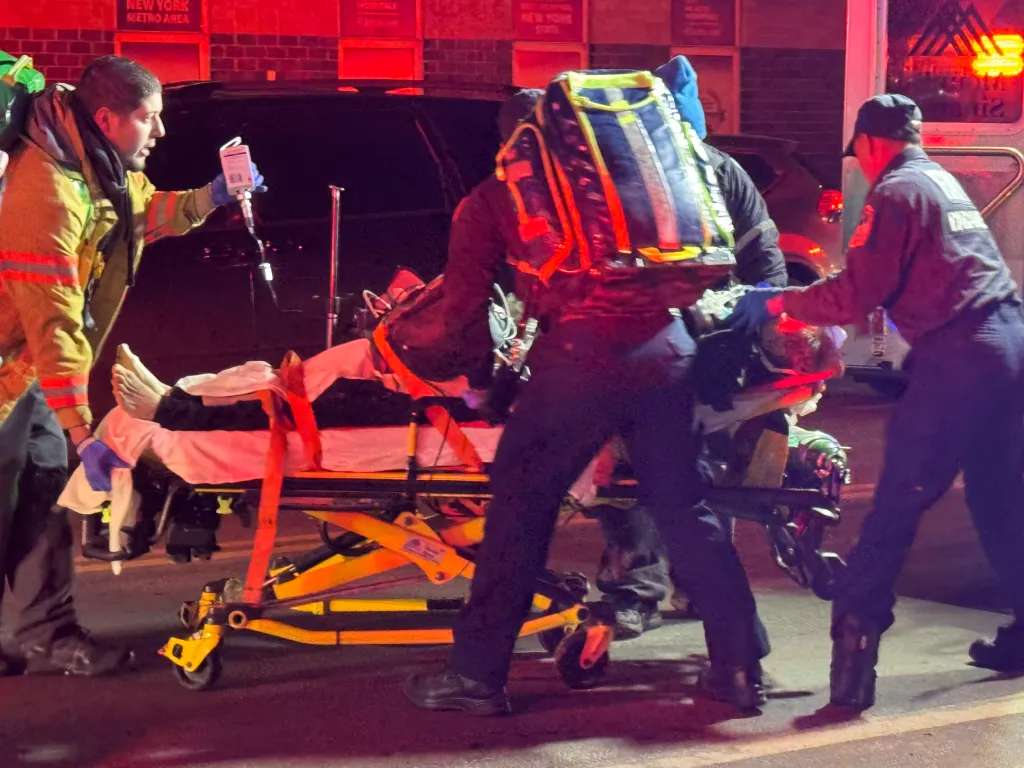 Paramedics attending to a patient on a stretcher at an all-hands fire scene.