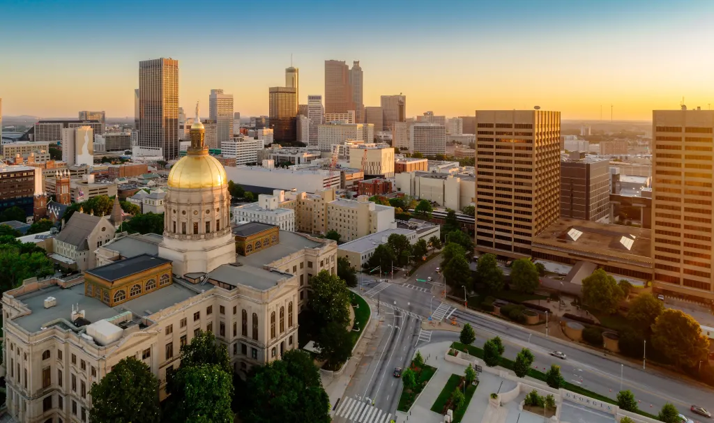 Aerial view of the Georgia State Capitol building and the Atlanta city skyline at sunset.