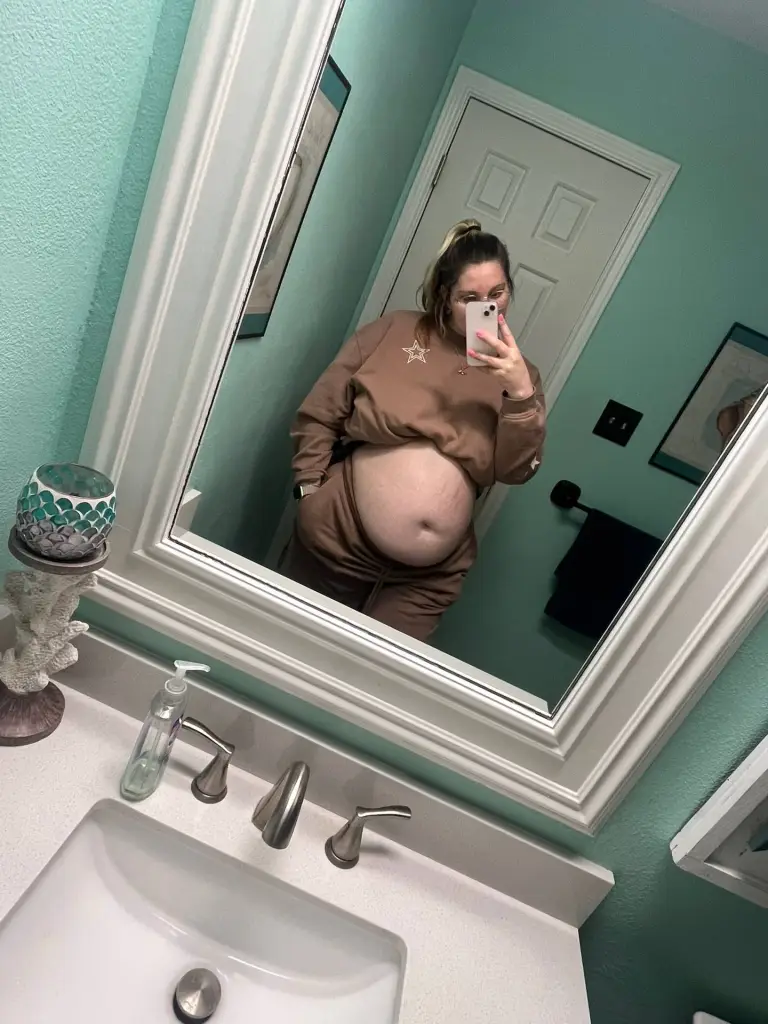 Pregnant woman Kayla Elliot in a brown outfit taking a mirror selfie.