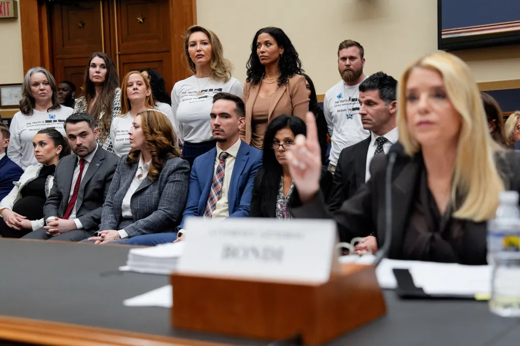 Survivors of Jeffrey Epstein stand at a House Judiciary Committee hearing while Attorney General Pam Bondi is questioned.