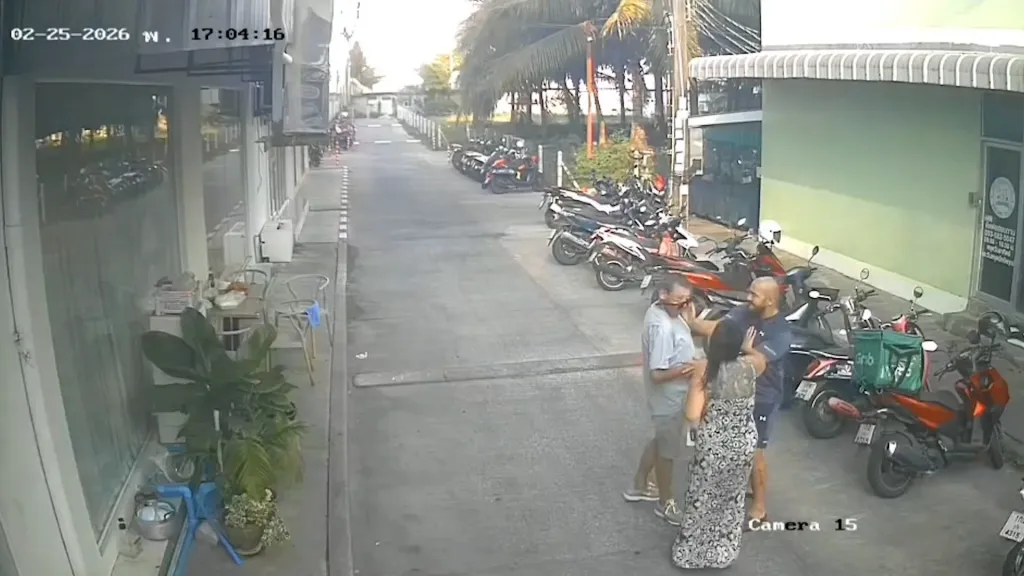 CCTV footage of a man in a black t-shirt striking another man in a white t-shirt while a woman stands between them.