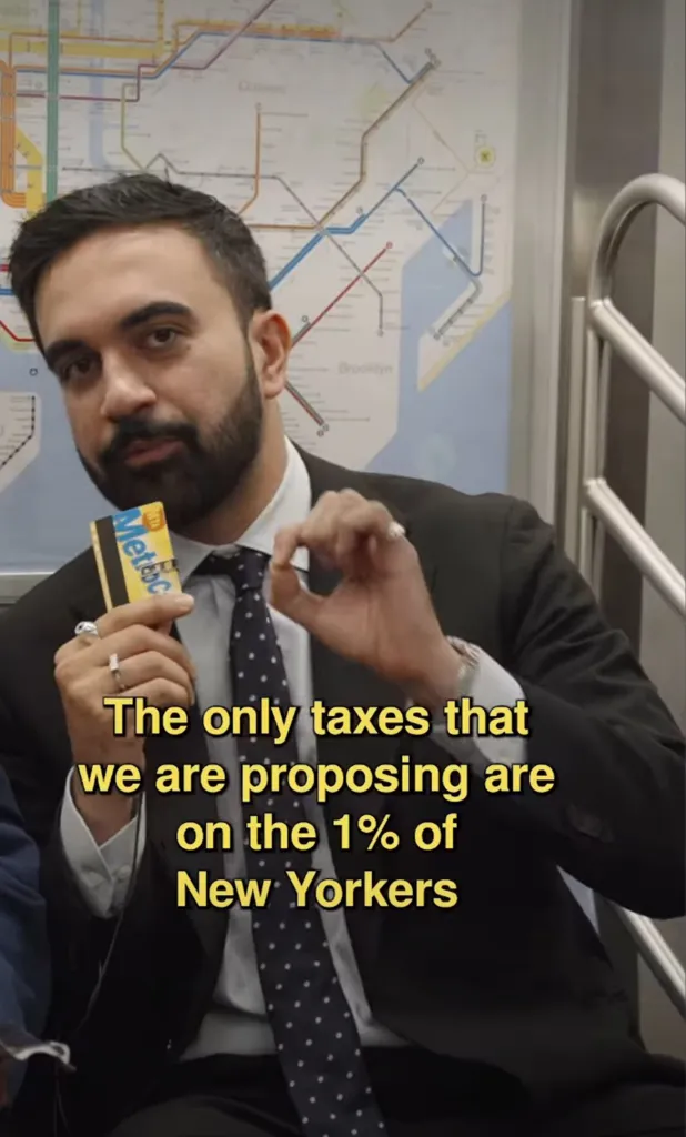 Zohran Mamdani on a subway holding a MetroCard, discussing tax raises.