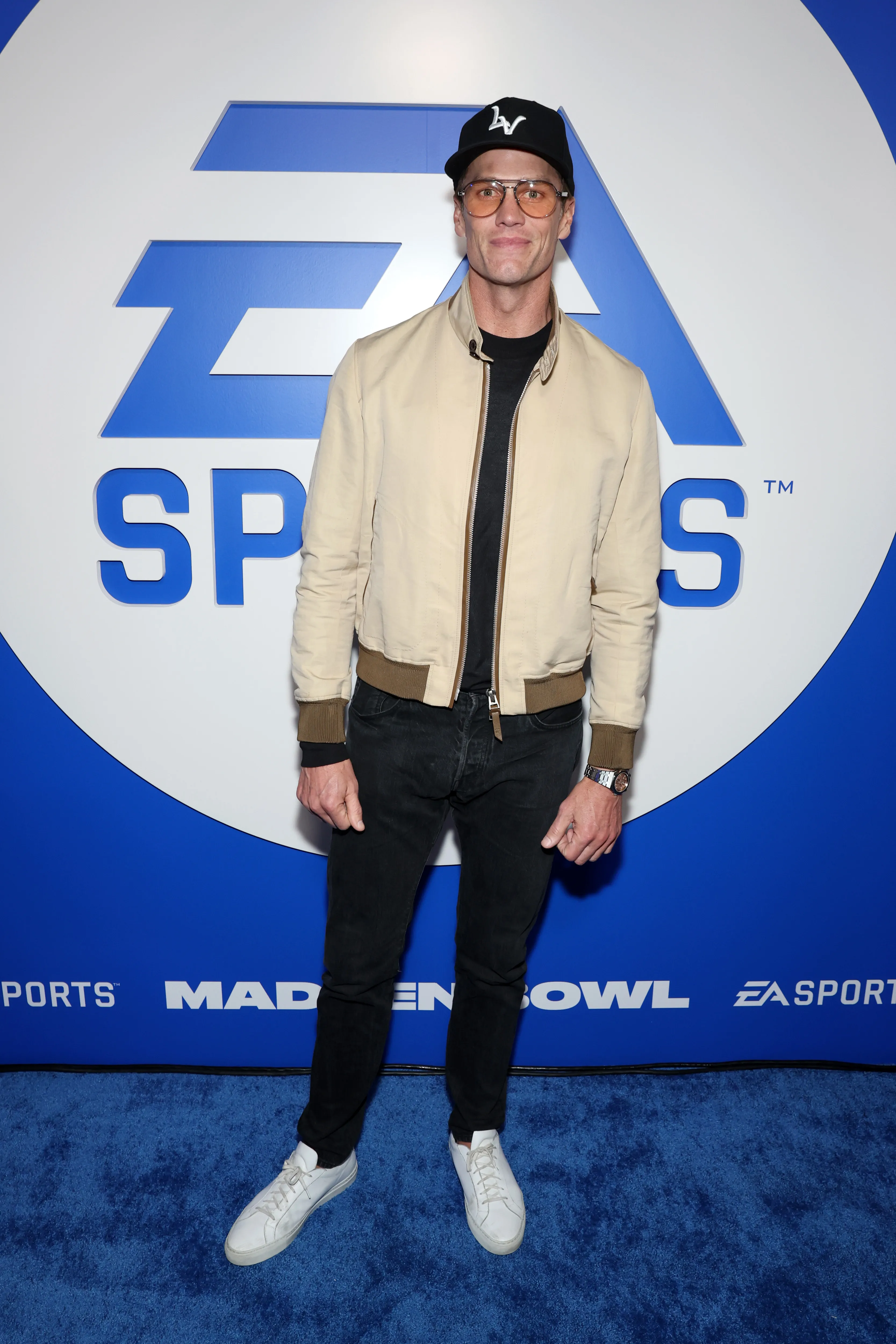 Tom Brady on a blue carpet in front of an EA Sports logo.