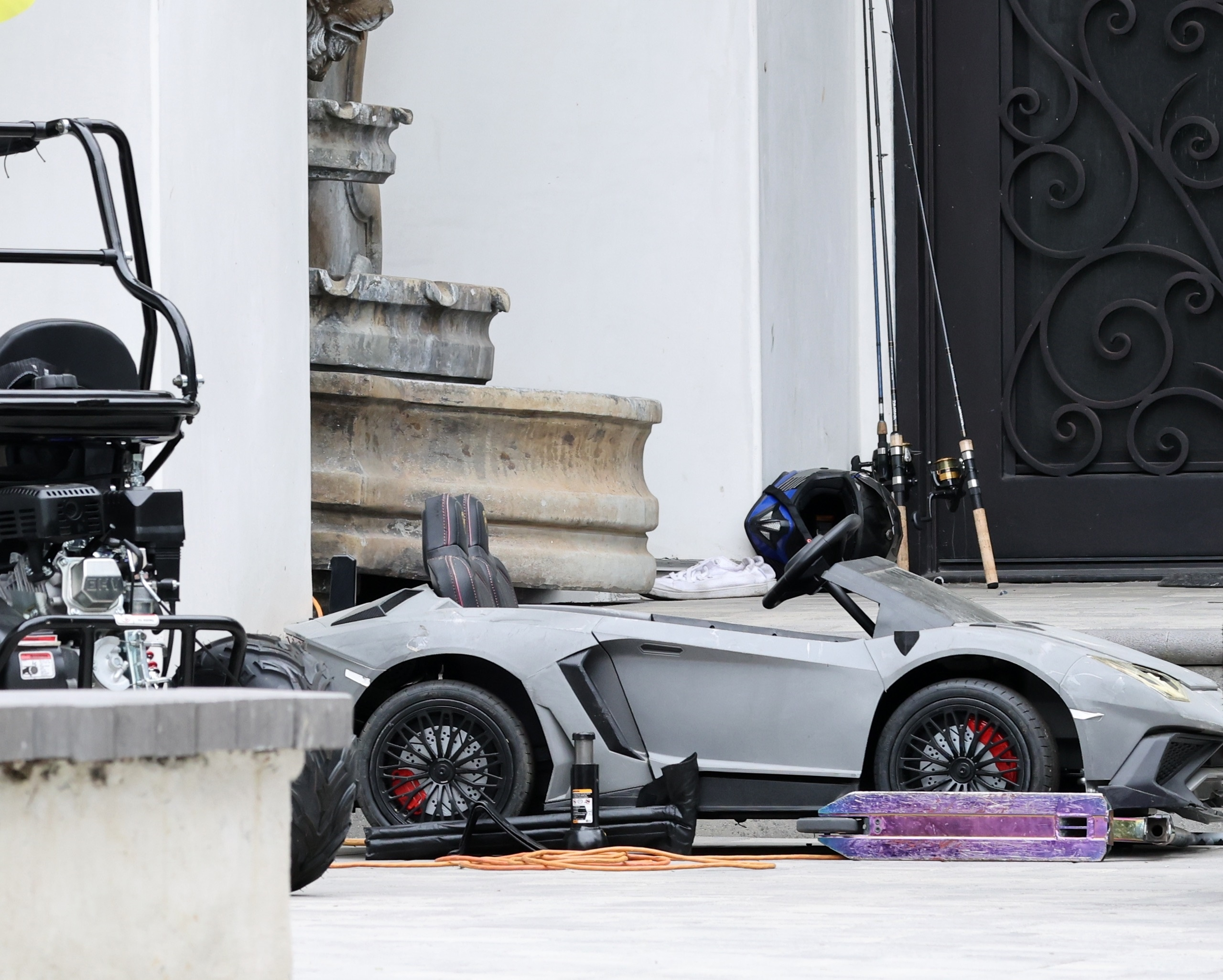 Tori Spelling's rental home with an ATV, motorized kids car, scooter, and fishing rods outside.