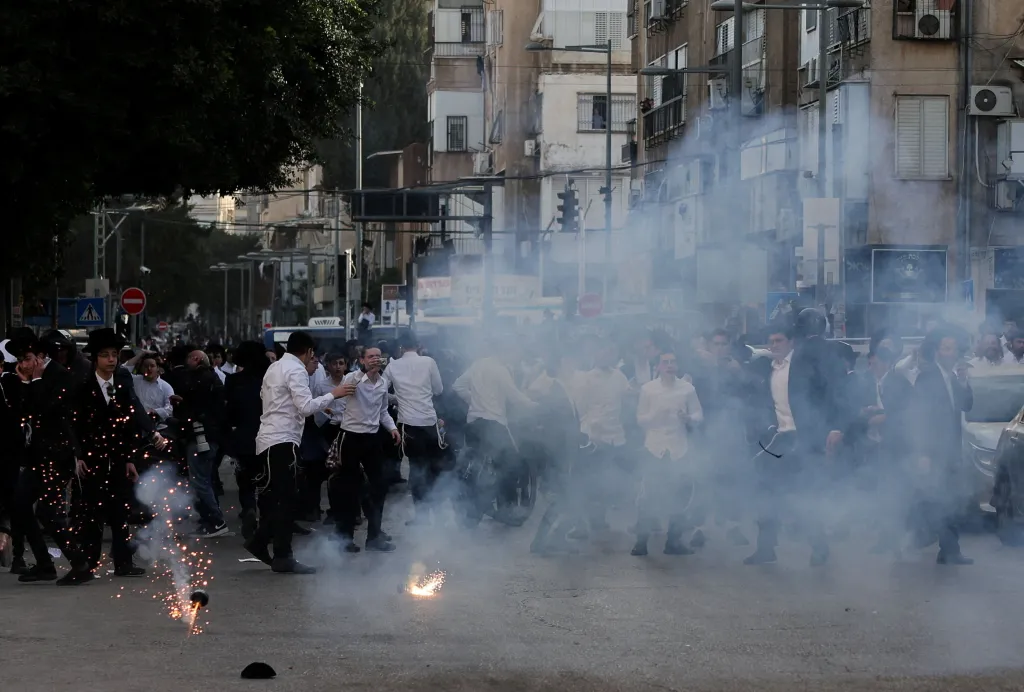 Ultra-Orthodox Jewish men react to a stun grenade during a protest against conscription into Israel's military.