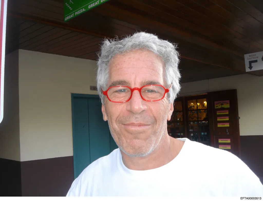 Jeffrey Epstein smiling and wearing red glasses.