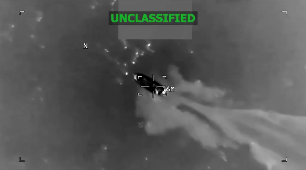 Infrared image of a boat moving quickly across water, leaving a trail of white foam, with the word 