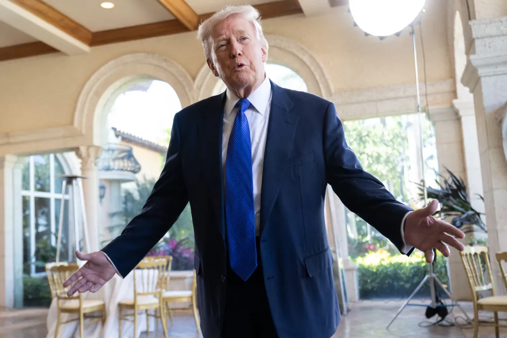 Donald Trump speaking at an event, with his arms outstretched.