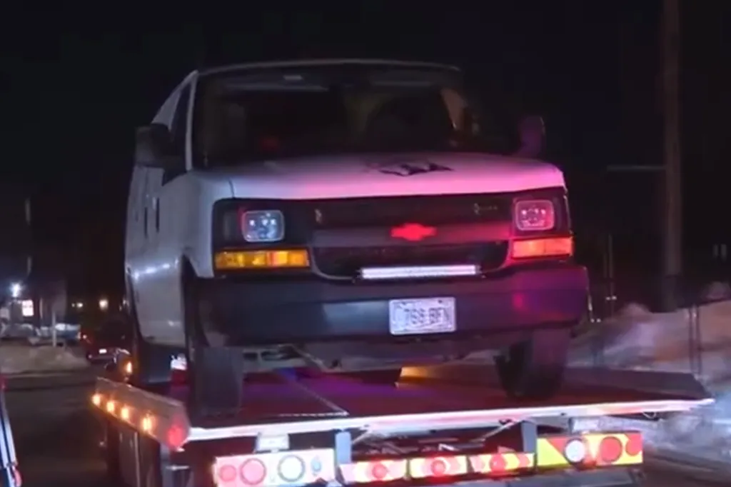 White van on the back of a tow truck at night.