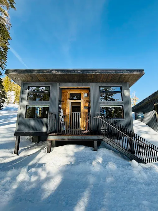 A Frog Lake Backcountry Hut in Lake Tahoe, CA, covered in snow with skis leaning against the front.