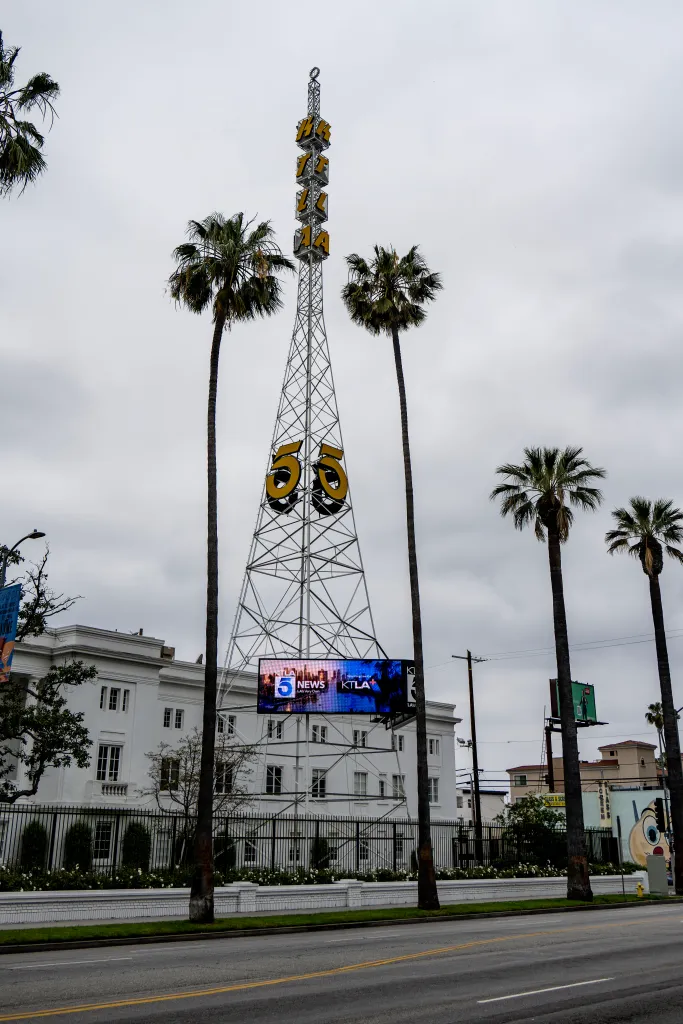 Historic KTLA 5 tower at Sunset Bronson Studios with palm trees and a large screen displaying 