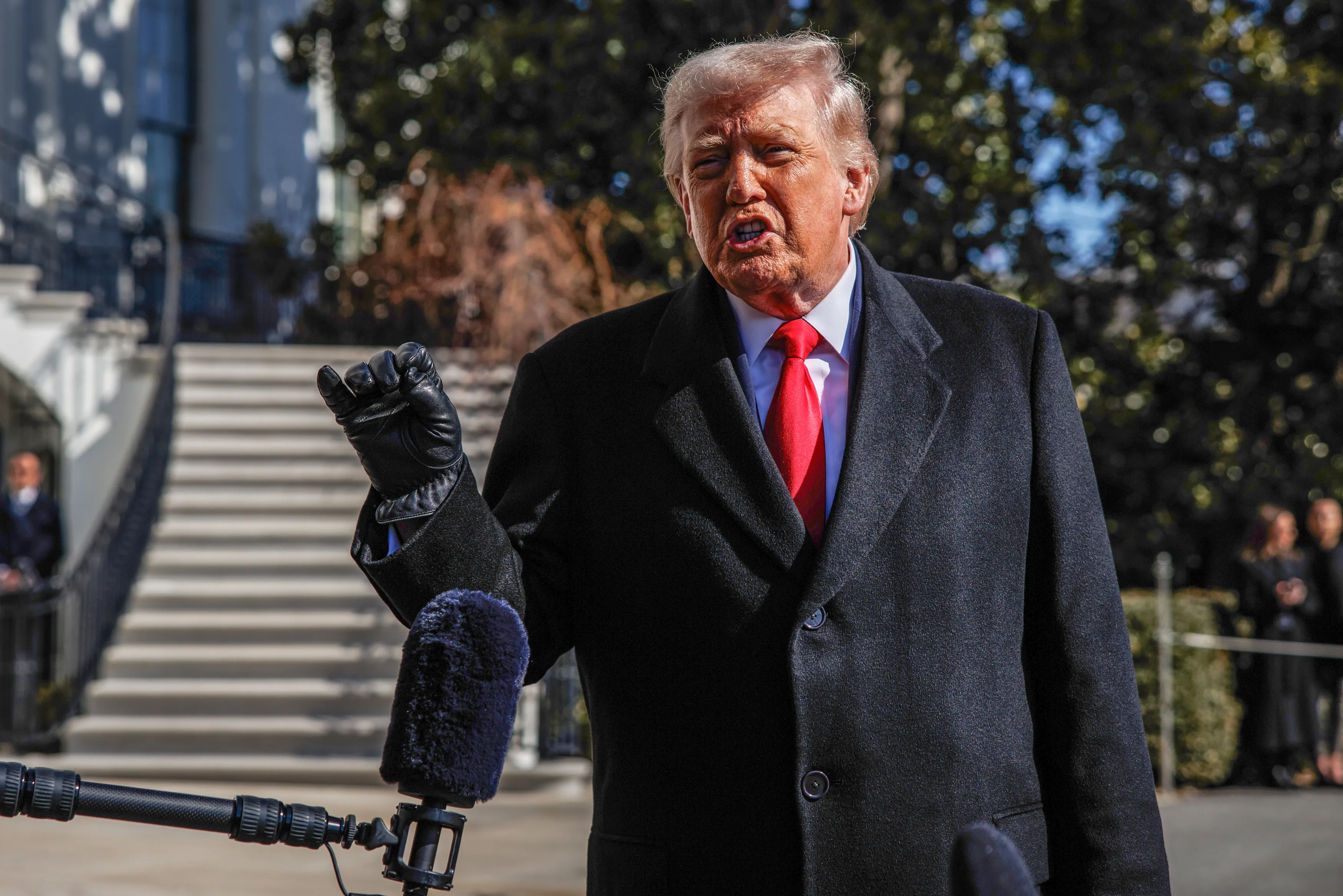 Donald Trump speaking to reporters with a microphone in front of him.
