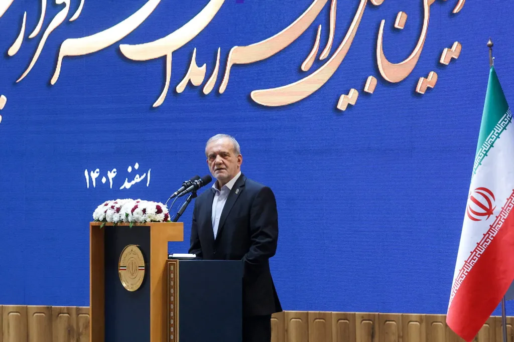 Iranian President Masoud Pezeshkian speaks at a podium during a meeting in Tehran.
