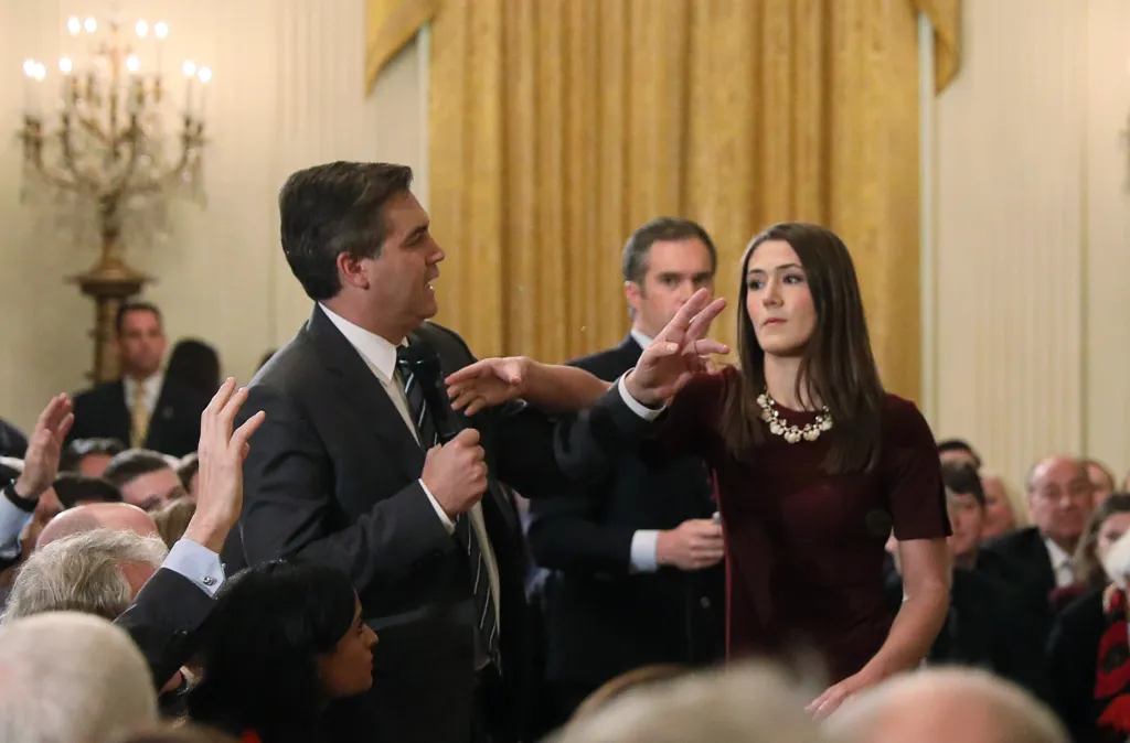 A White House intern reaching for a microphone held by CNN correspondent Jim Acosta during a news conference.