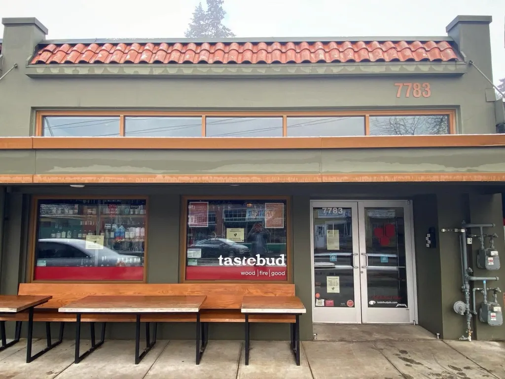 The exterior of the Tastebud pizza restaurant with outdoor seating.