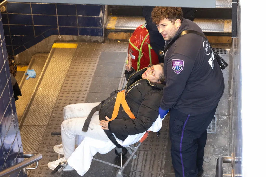 Paramedics transporting a woman to the hospital after she was pushed onto subway tracks.