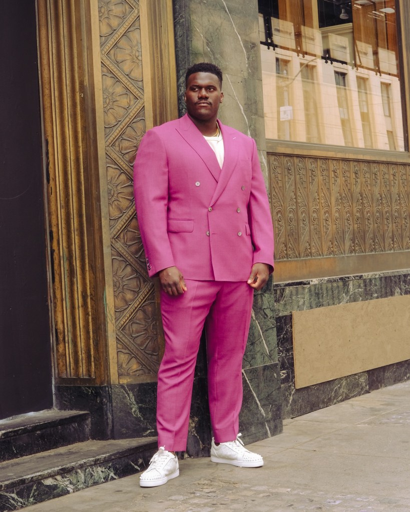Olusegun Oluwatimi in a bright pink double-breasted suit and white sneakers with spiked toes.