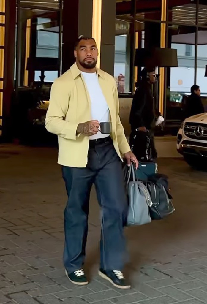 Leonard Williams walks with a cup and bags.