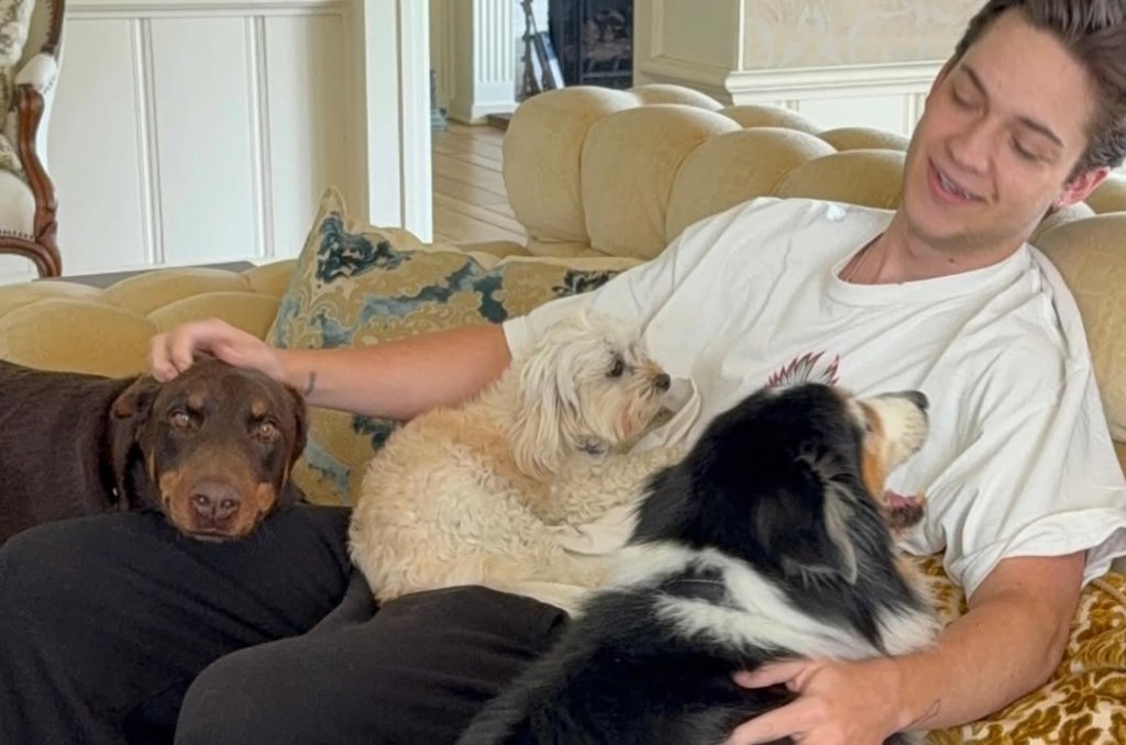 Ryder Robinson petting his dogs on a couch.