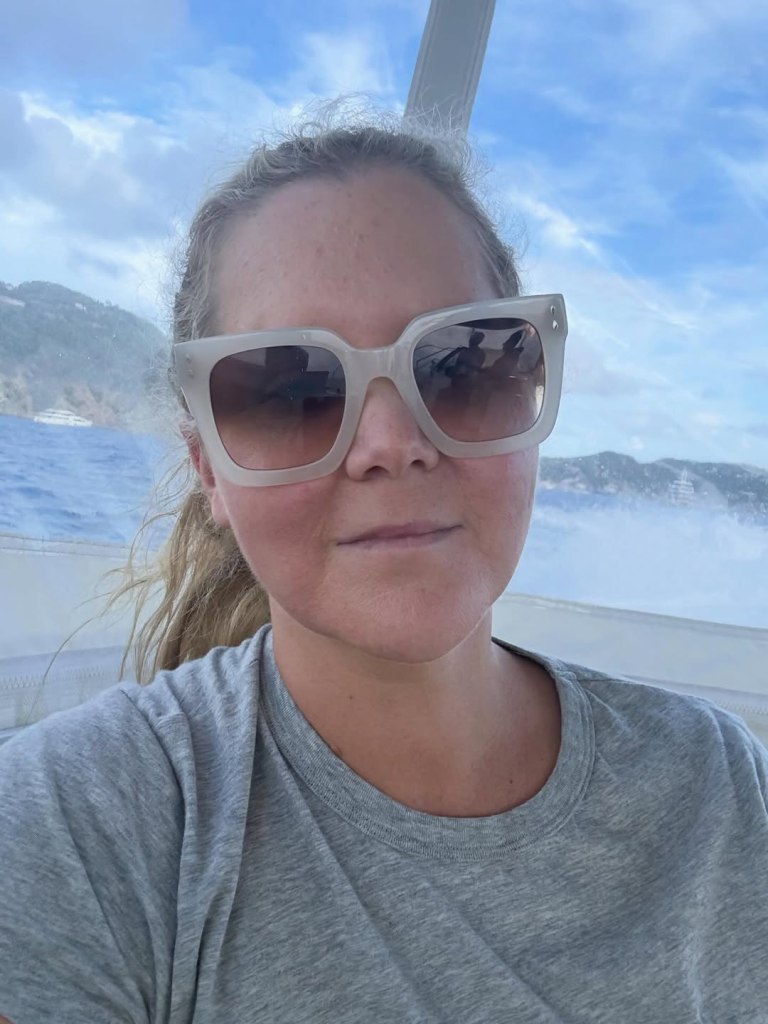 Amy Schumer wearing large sunglasses on a boat.