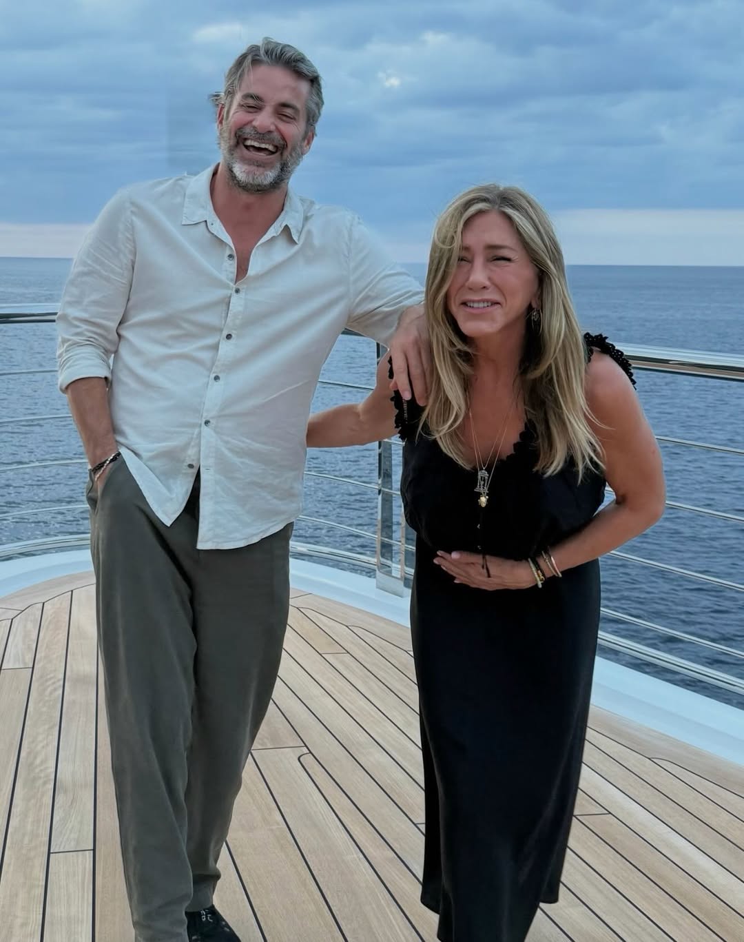 Jennifer Aniston and Jim Curtis laughing on a yacht.