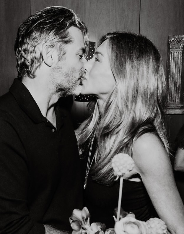 Black and white photo of Jennifer Aniston and Jim Curtis kissing.