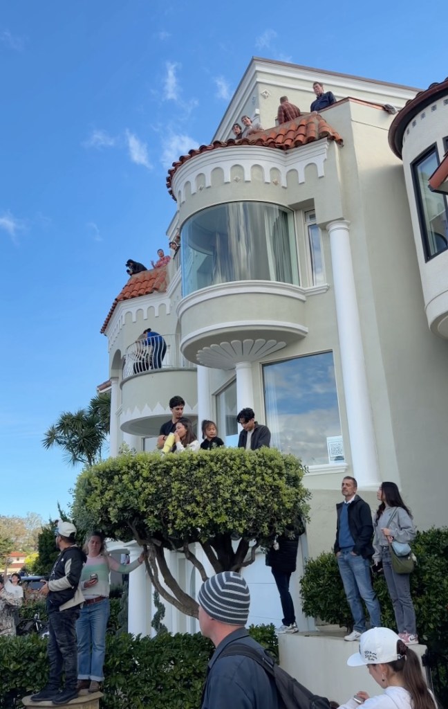 People watching from balconies and roof of a multi-story building.