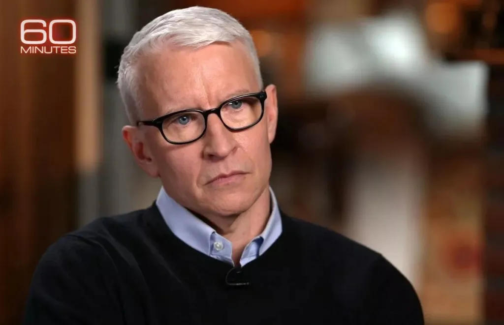 Anderson Cooper in a black sweater and light blue shirt, with 