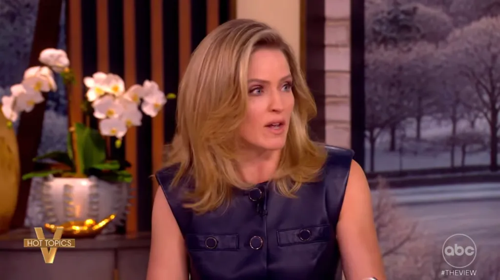 Sara Haines wearing a dark blue top with gold buttons.