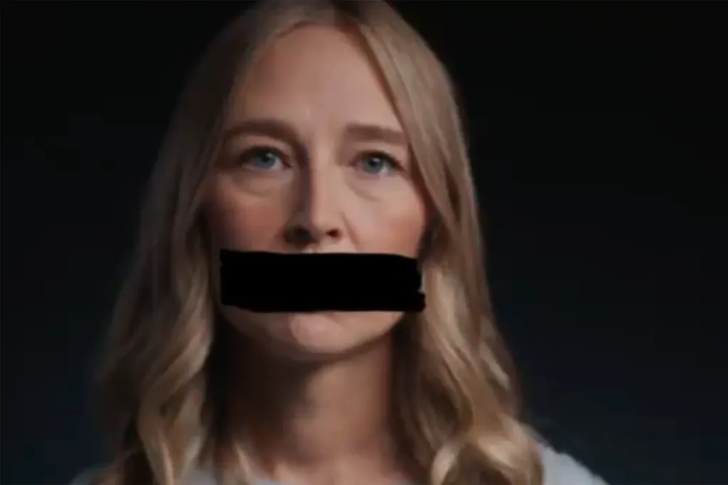 A blonde woman with a black bar over her mouth, implying silence.