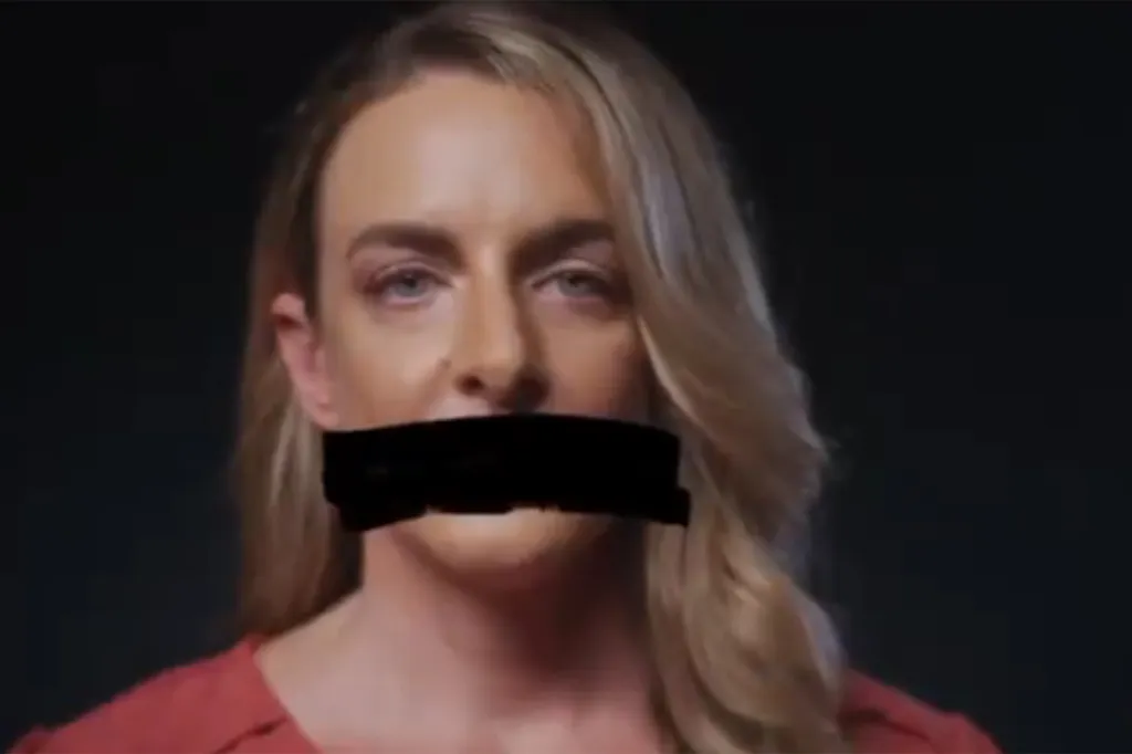A woman with light hair and a black bar over her mouth, symbolizing censorship or silencing.