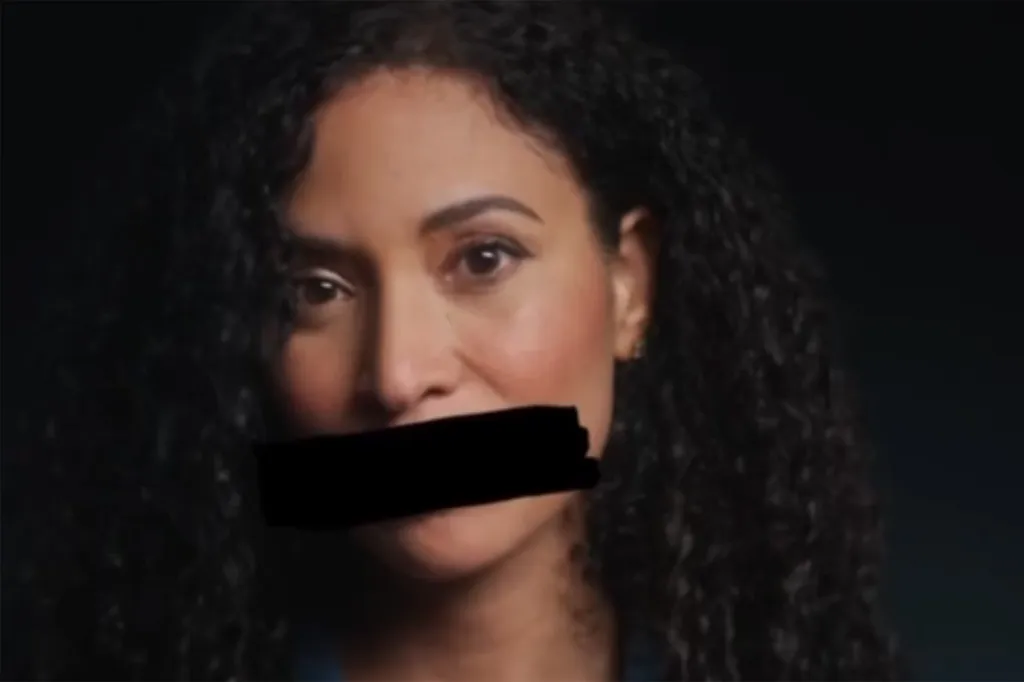 A woman with dark curly hair and dark eyes, with her mouth obscured by a black rectangle, representing a silenced victim.