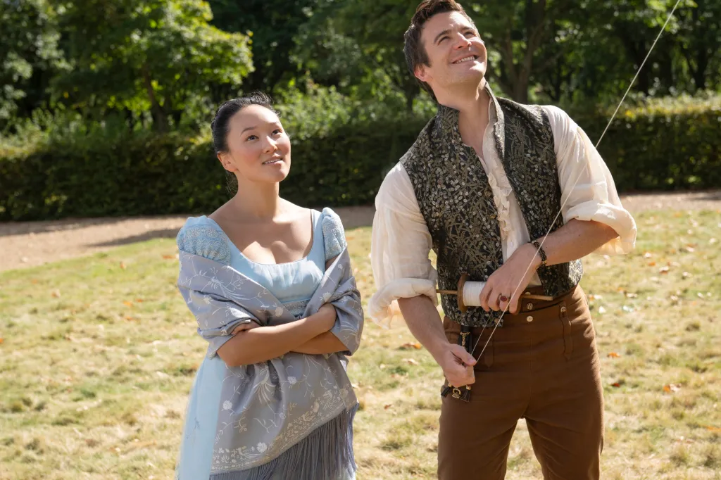 Yerin Ha and Luke Thompson in period clothing, flying a kite.